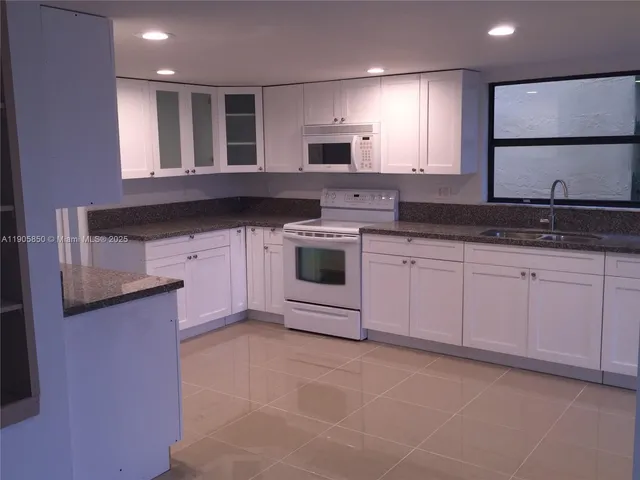 a kitchen with granite countertop a sink a stove and cabinets