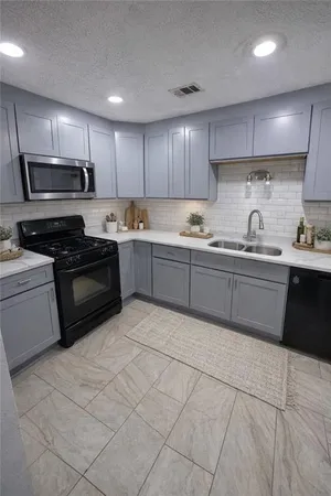 a kitchen with granite countertop a sink and steel appliances