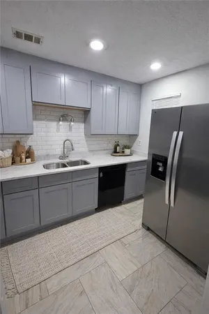a kitchen with granite countertop a refrigerator a sink and wooden cabinets