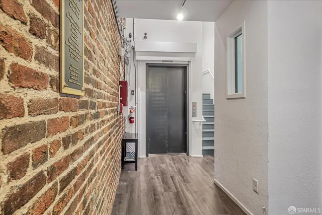 view of wooden floor and brick walls