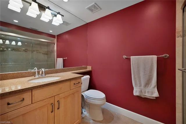 a bathroom with a granite countertop toilet sink and mirror