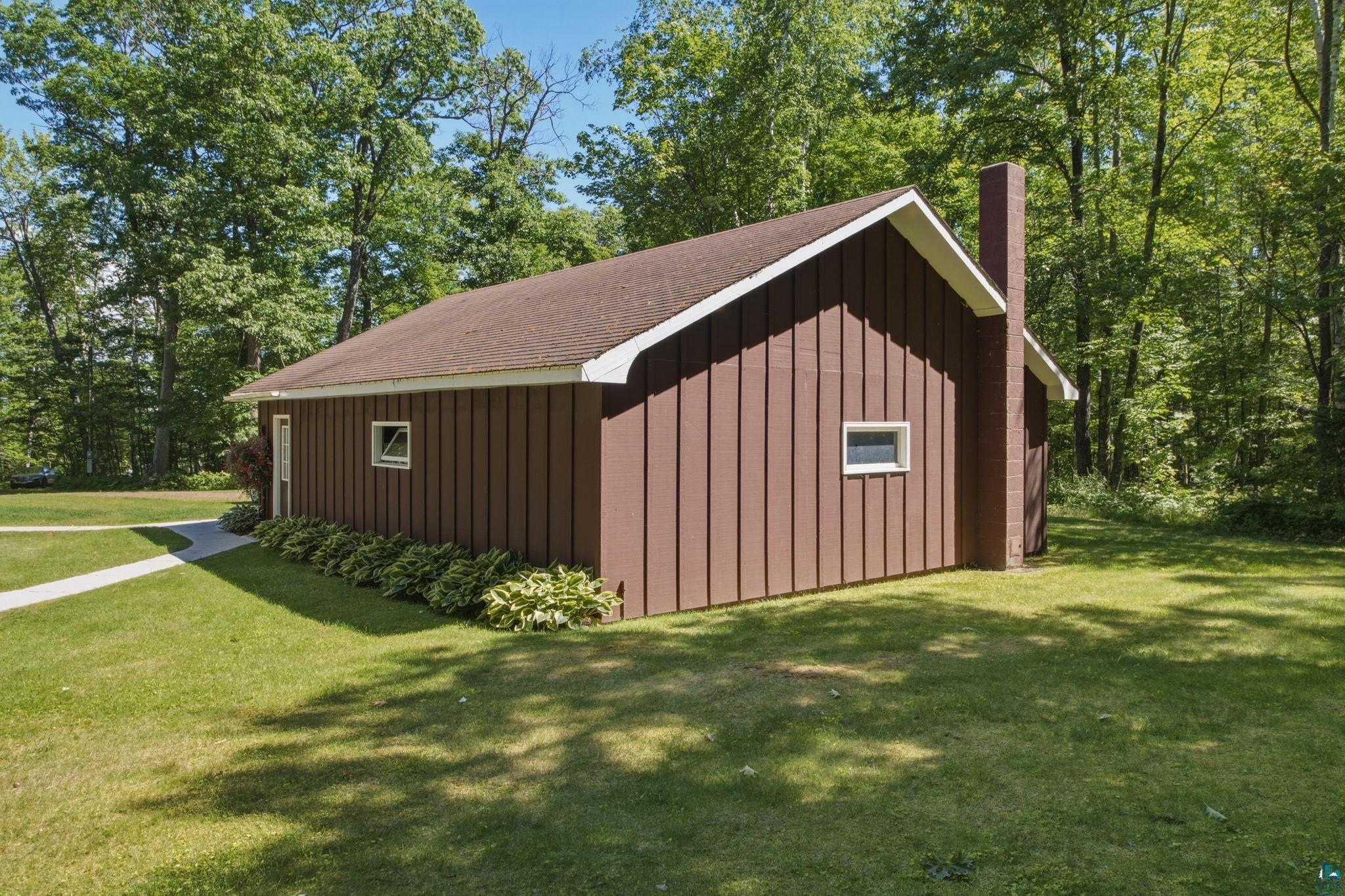 27485 South Kane Road Ashland, WI 54806 - Photo 26 of 35 Brown vertical siding on the exterior, featuring a brown shingle roof, a brick chimney, and white trim