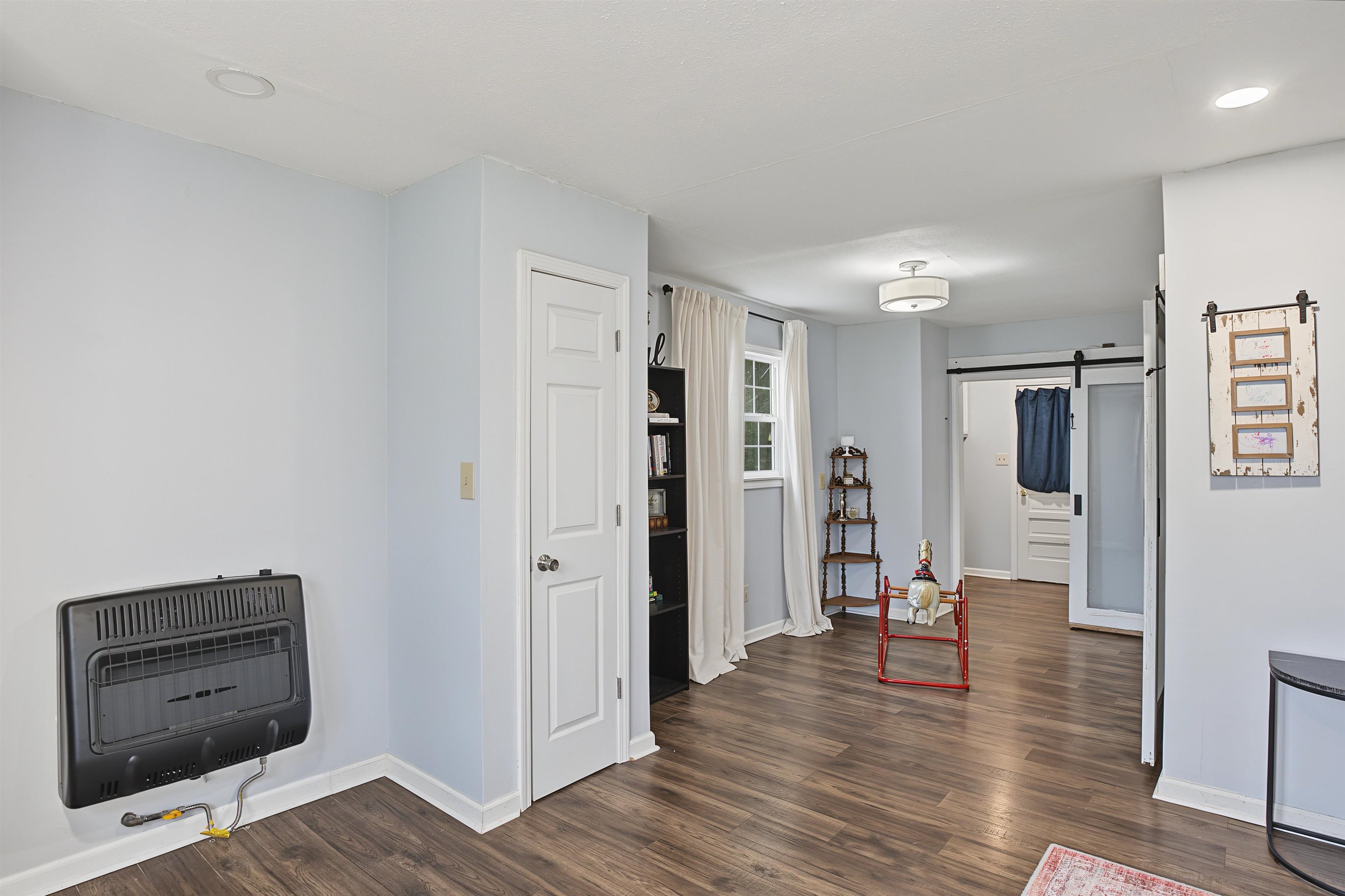 246 Cherryville Road Bells, TN 38006 - Photo 12 of 31 Wood-finish flooring, recessed ceiling lighting, wall-mounted heating unit, and a barn door entry