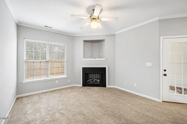 a view of an empty room with chandelier fan and fire place