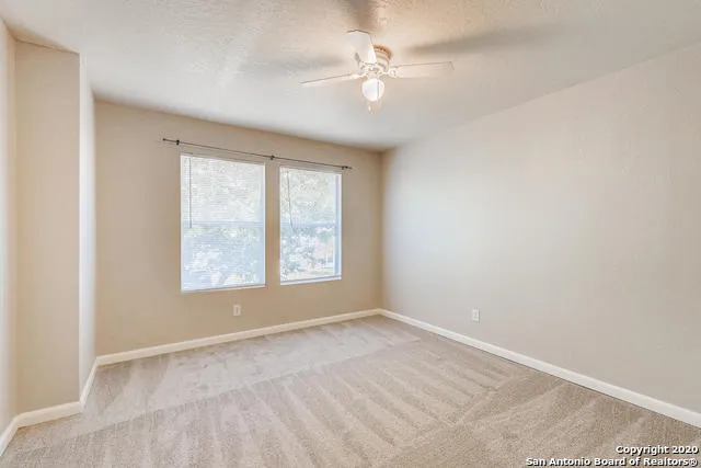 an empty room with a window and a fan