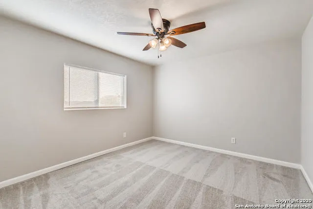 an empty room with a window and a fan