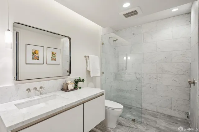a bathroom with a granite countertop sink a toilet and a mirror