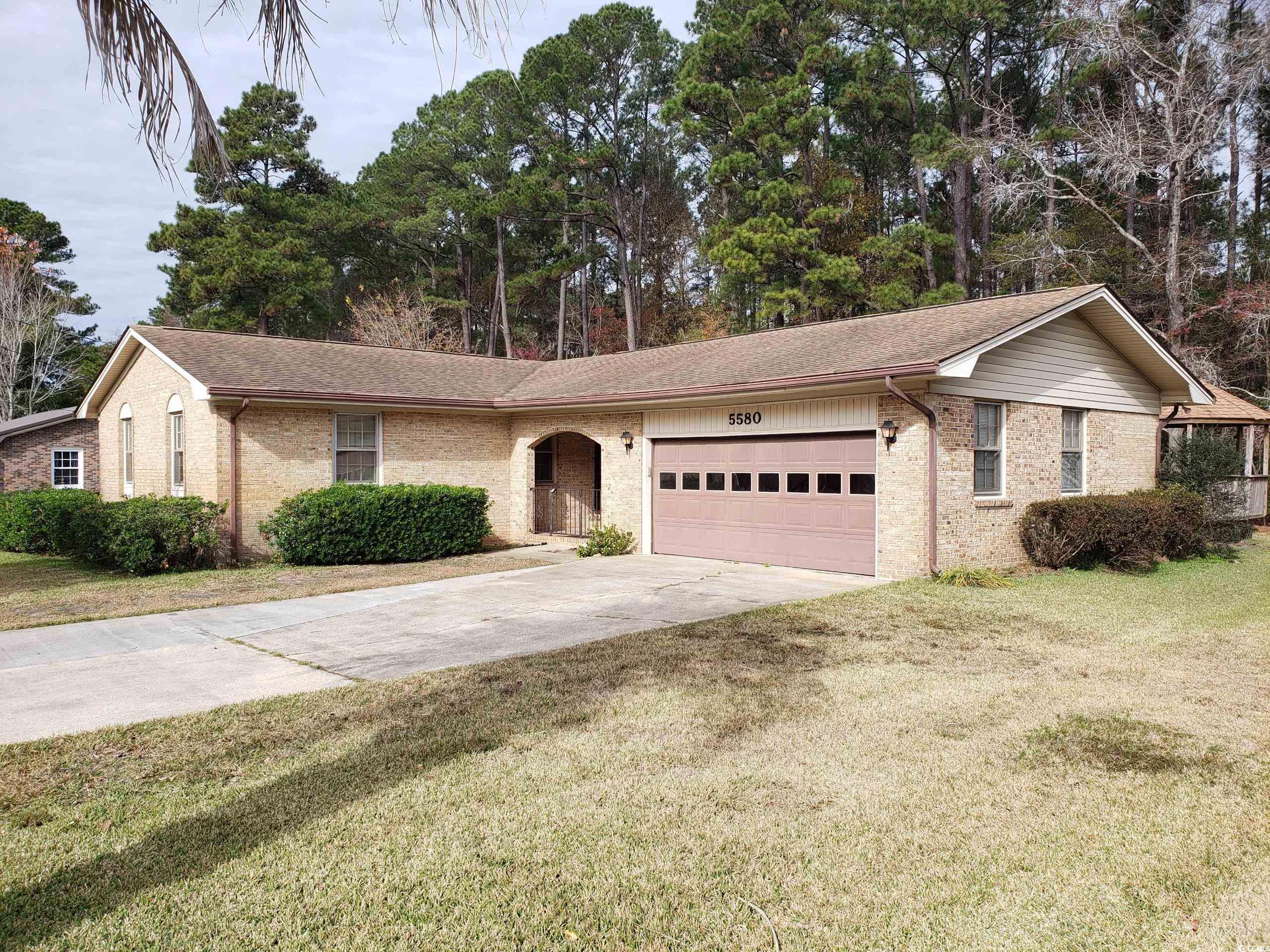Single story home featuring a front yard, an attached garage, concrete driveway, and brick siding