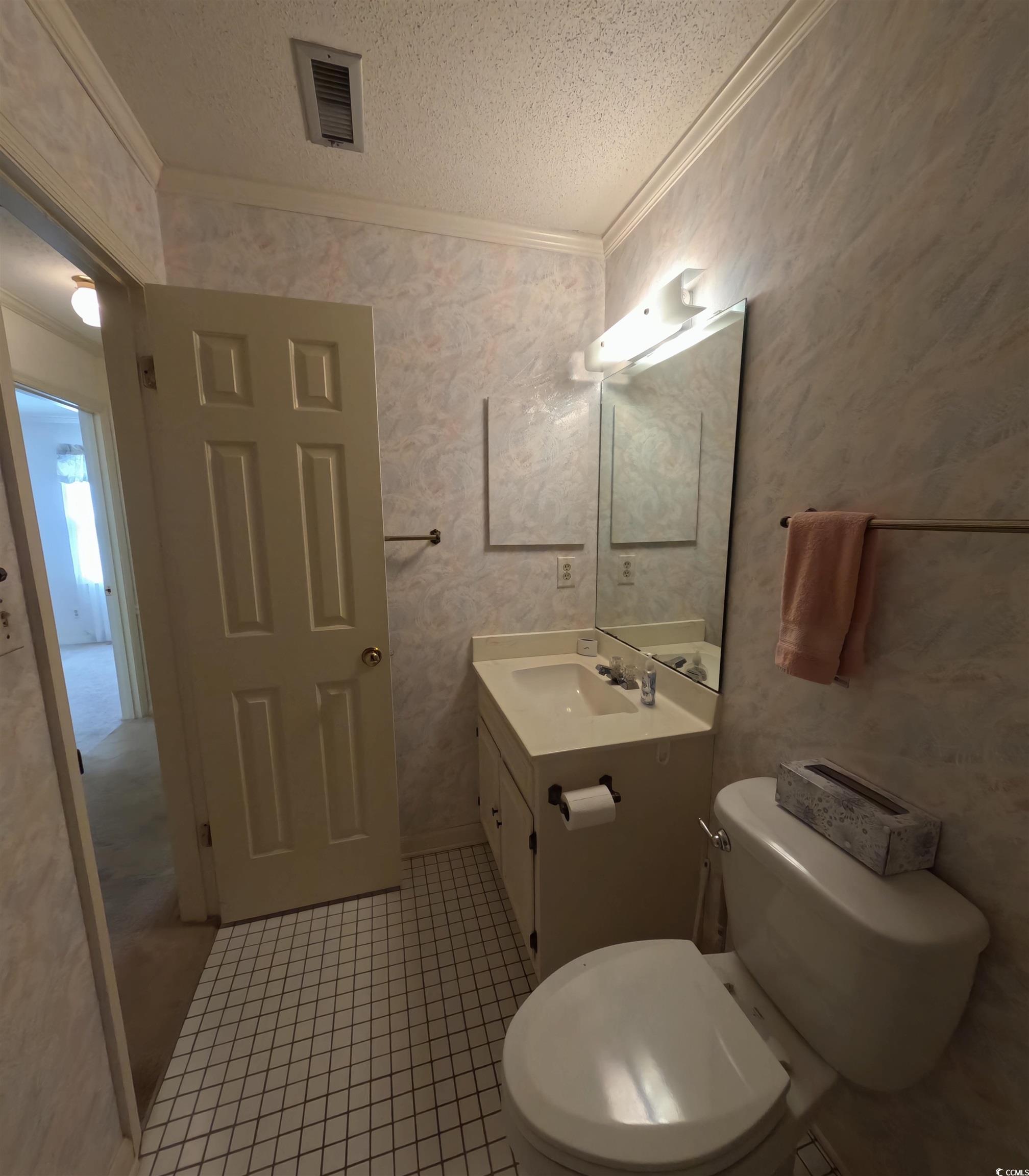 5580 Green Bay Circle Myrtle Beach, SC 29588 - Photo 12 of 36 Bathroom with crown molding, vanity, a textured ceiling, wallpapered walls, and light tile patterned flooring