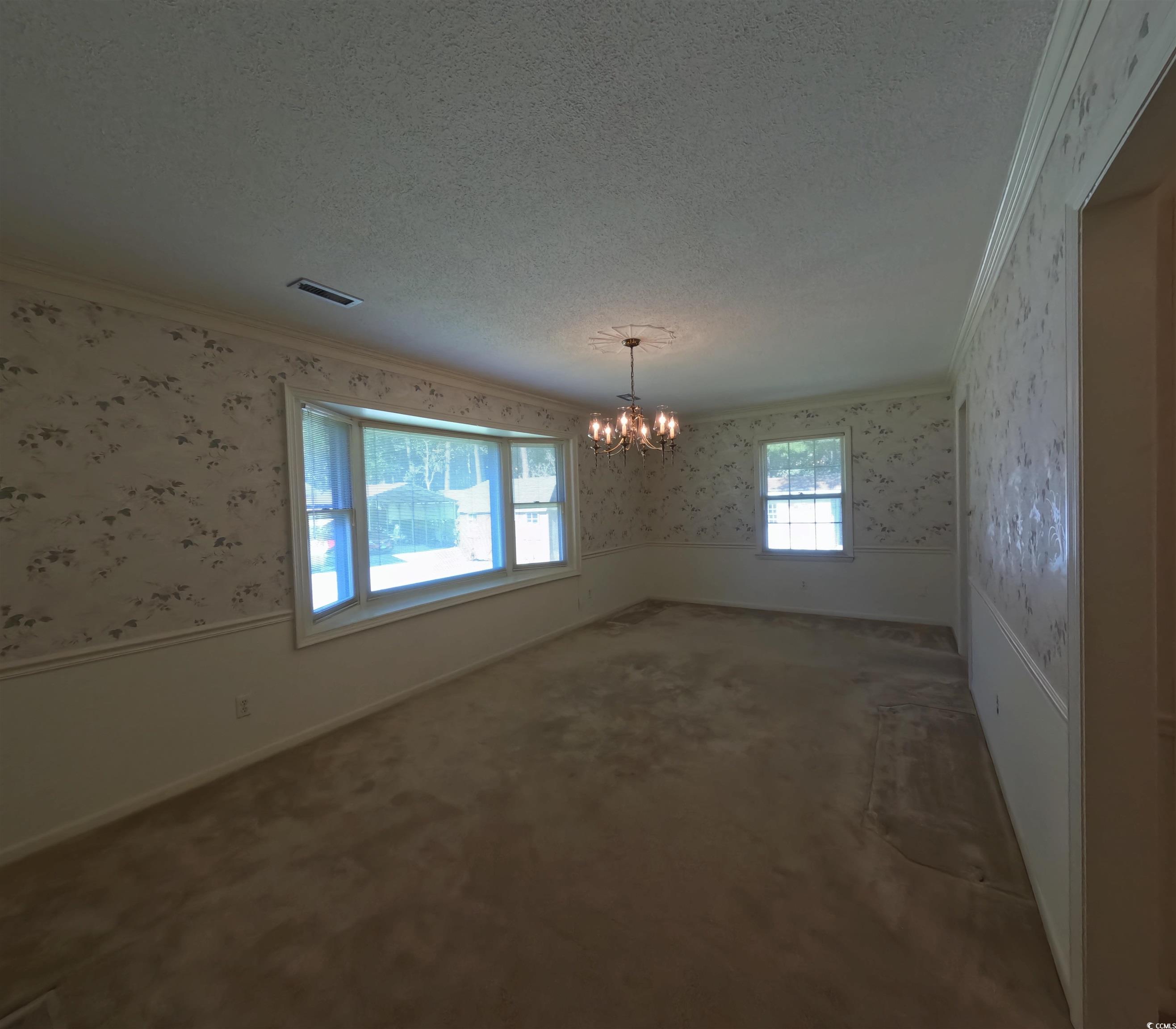5580 Green Bay Circle Myrtle Beach, SC 29588 - Photo 3 of 36 Empty room featuring wallpapered walls, wainscoting, healthy amount of natural light, ornamental molding, and a chandelier