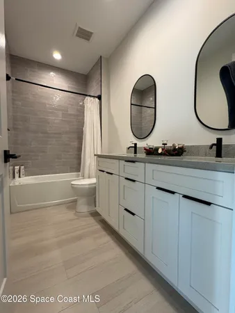 a bathroom with a double vanity sink mirror toilet and bathtub