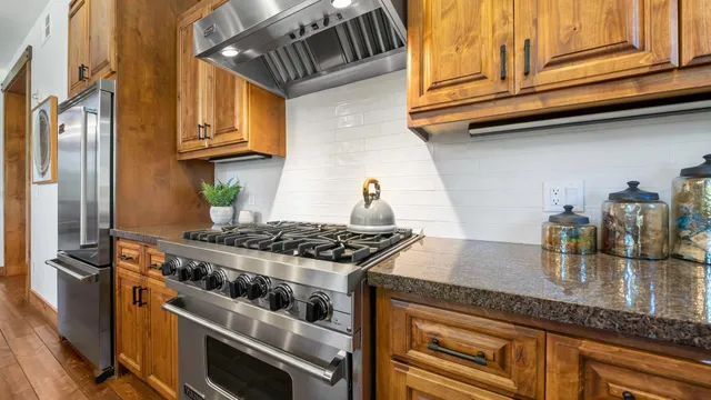 a kitchen with stainless steel appliances granite countertop a stove a sink and a refrigerator