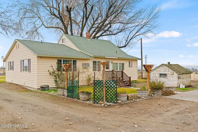 a view of a house with a large tree and wooden fence