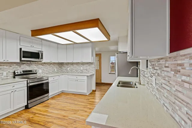 a kitchen with granite countertop a sink cabinets stainless steel appliances and a counter top space