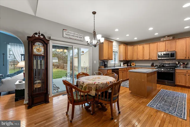 a kitchen with stainless steel appliances granite countertop a stove top oven a sink dishwasher a dining table and chairs with wooden floor