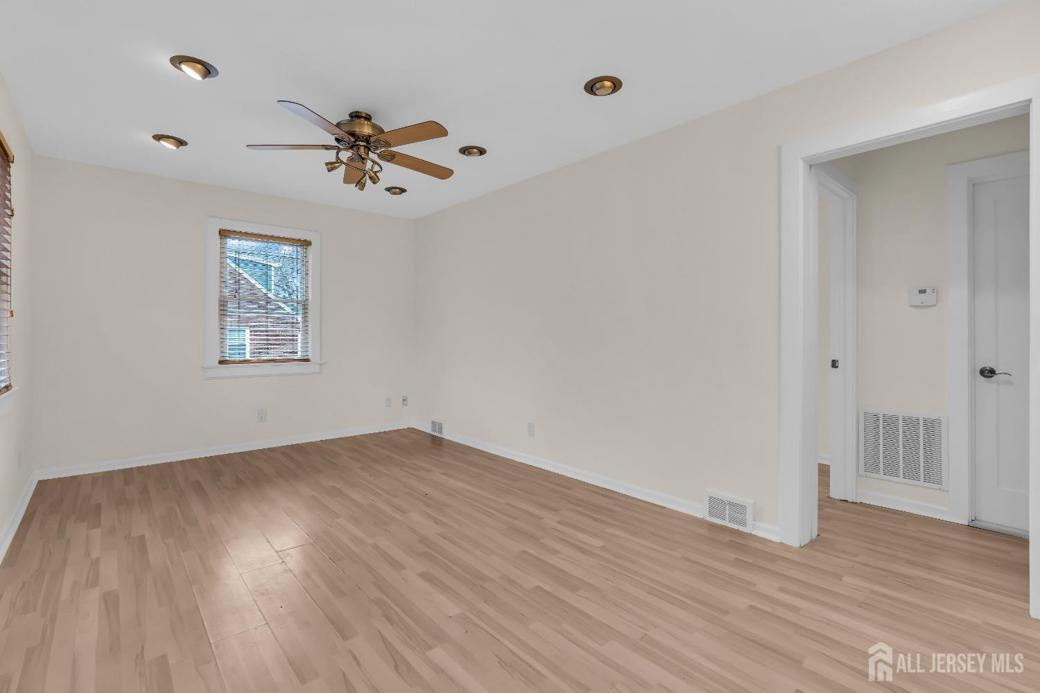 1550 Englishtown Road Old Bridge, NJ 08857 - Photo 8 of 20 an empty room with wooden floor chandelier fan and windows
