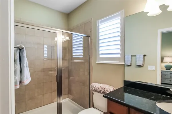 a bathroom with a granite countertop sink mirror vanity and toilet