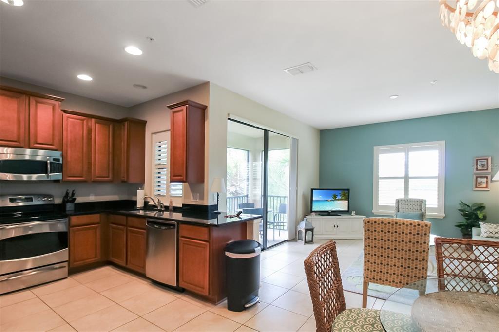 7333 Skybird Road Bradenton, FL 34209 - Photo 24 of 35 a kitchen with stainless steel appliances granite countertop a stove a sink dishwasher a microwave oven and a dining table with wooden floor
