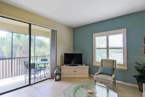 a living room with furniture a flat screen tv and a floor to ceiling window