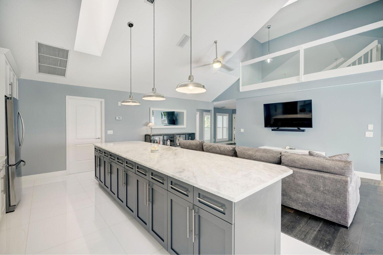 141 Pine Hill Trail West Tequesta, FL 33469 - Photo 22 of 53 a large white kitchen with a large island a stove a sink and a living room view