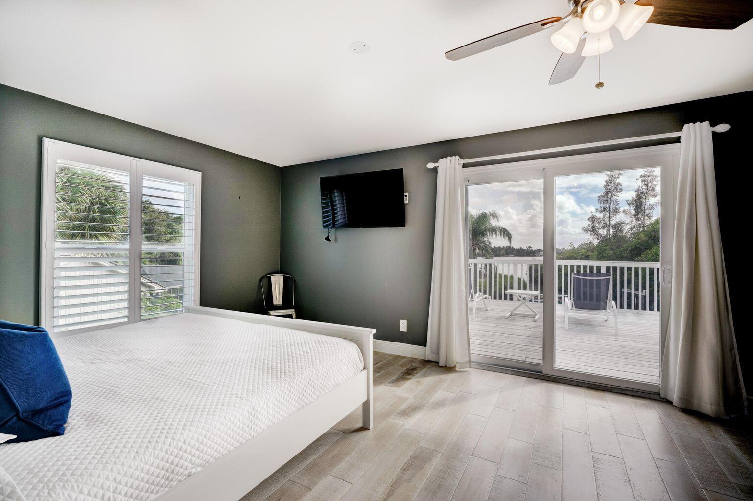 141 Pine Hill Trail West Tequesta, FL 33469 - Photo 23 of 53 a bedroom with a balcony a bed and a flat screen tv