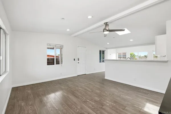a view of an empty room with kitchen and window