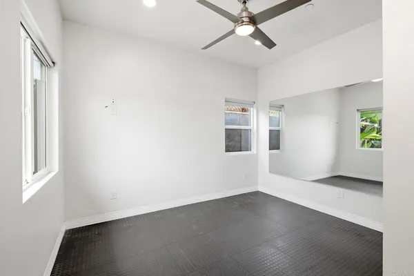 an empty room with windows and ceiling fan
