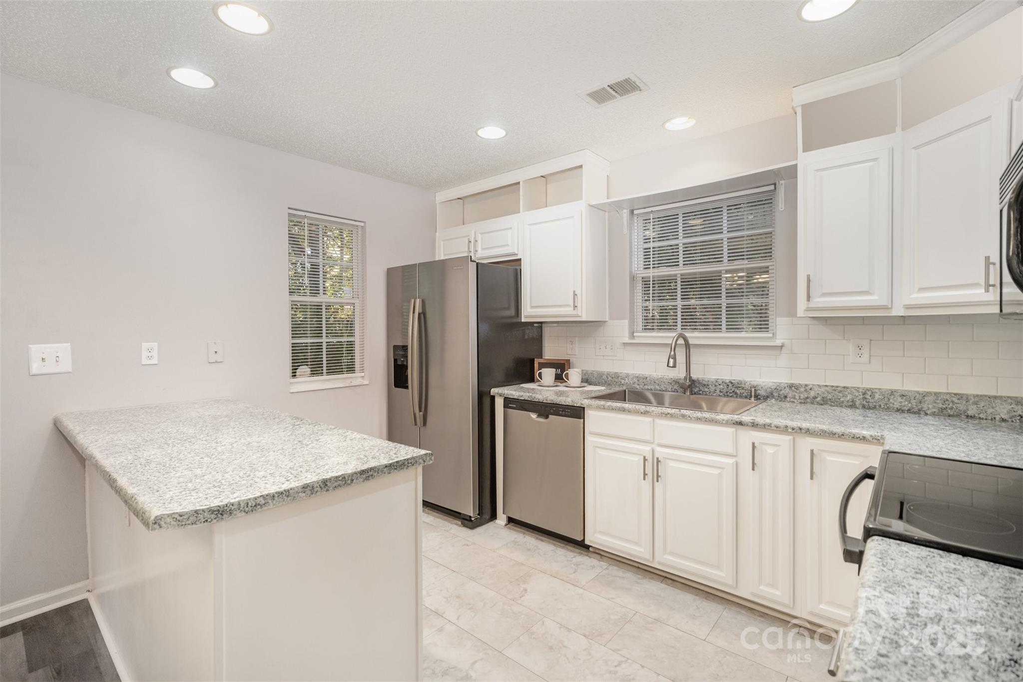 8230 Rudolph Road Charlotte, NC 28216 - Photo 4 of 38 a kitchen with stainless steel appliances granite countertop refrigerator sink and cabinets