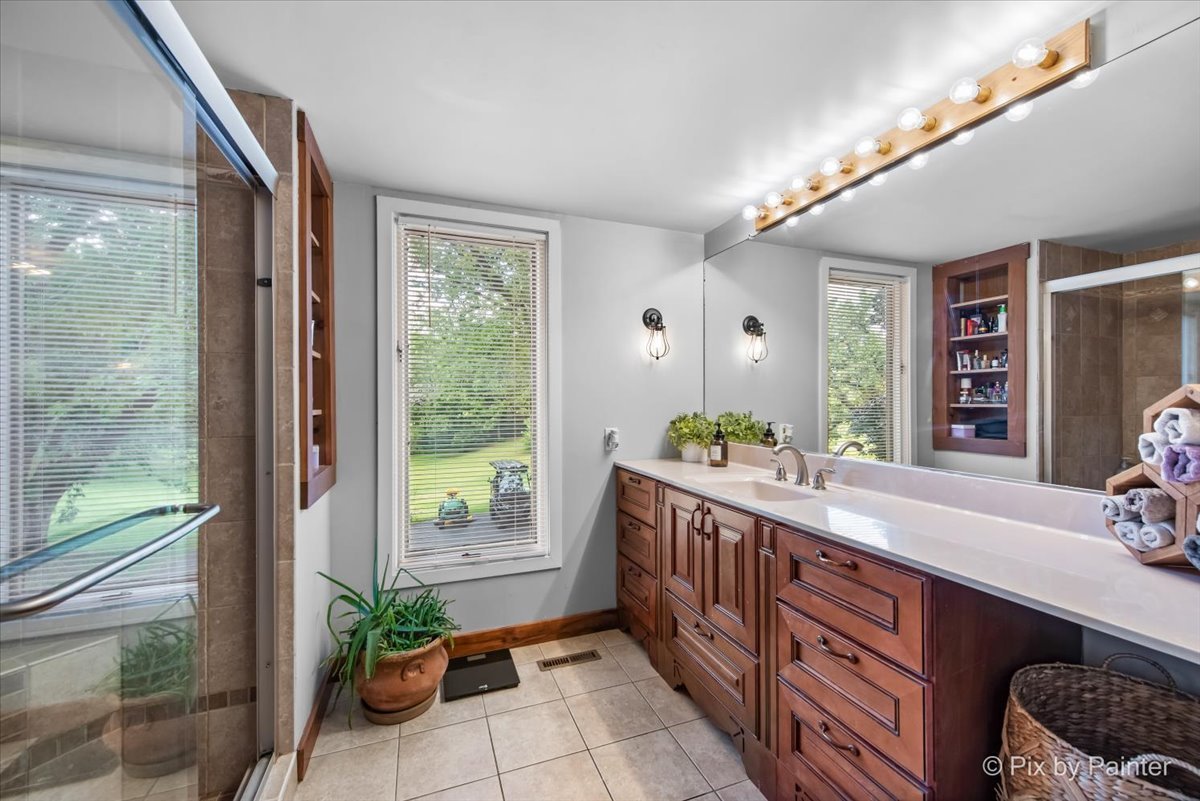 6111 Ridgeview Drive Huntley, IL 60142 - Photo 16 of 54 a bathroom with a granite countertop sink a mirror and a shower