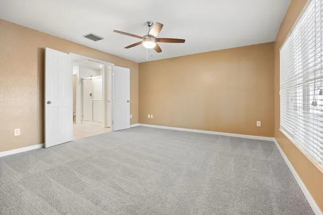 en empty room with windows and ceiling fan