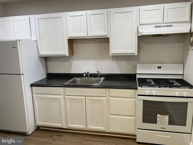 a kitchen with granite countertop white cabinets and stainless steel appliances