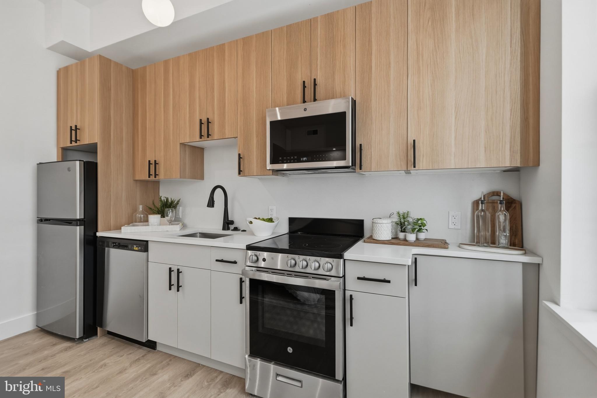 326 North 12th Street, Unit 201 Philadelphia, PA 19107 - Photo 12 of 22 a kitchen with stainless steel appliances granite countertop a stove a sink dishwasher and a refrigerator with wooden cabinets