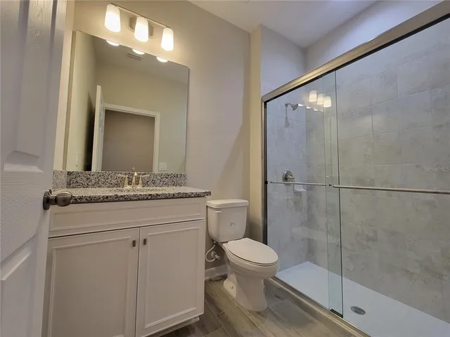 a bathroom with a granite countertop sink toilet and shower