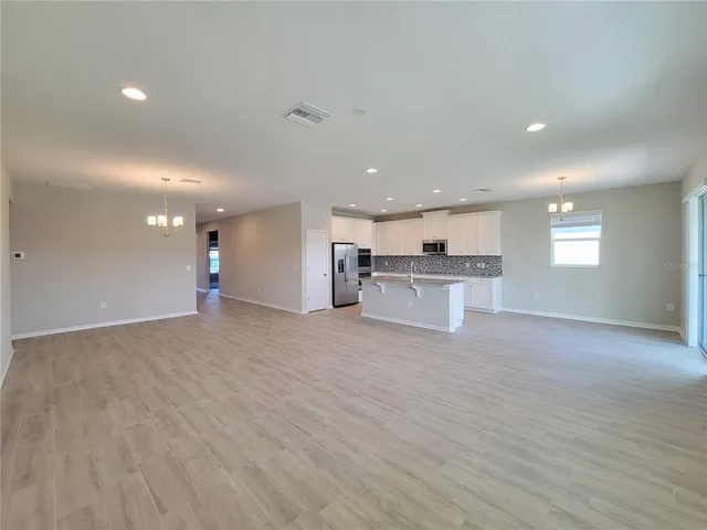 a view of kitchen and empty room with wooden floor