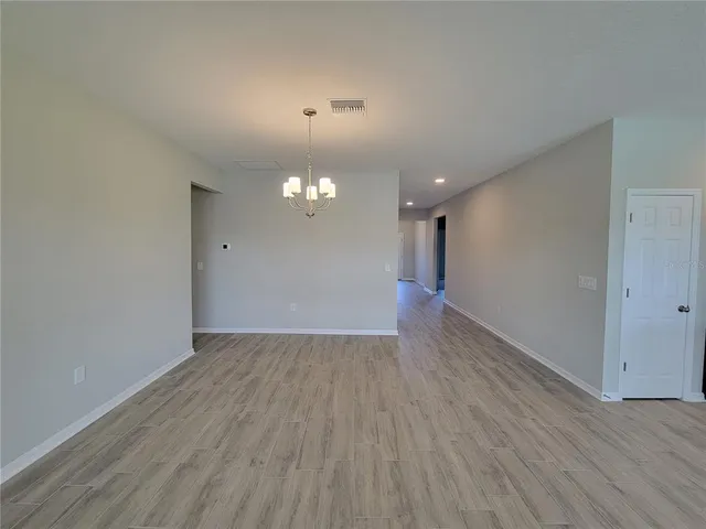 an empty room with wooden floor and chandelier