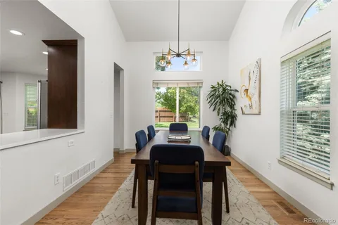 a dining room with chandelier and wooden floor