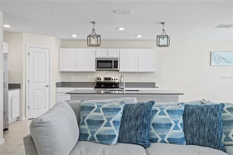 a kitchen with stainless steel appliances granite countertop a stove a sink a refrigerator a microwave a dining table and chairs