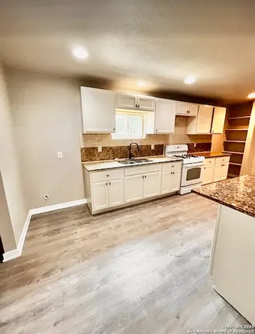 a large kitchen with stainless steel appliances granite countertop a stove and a sink