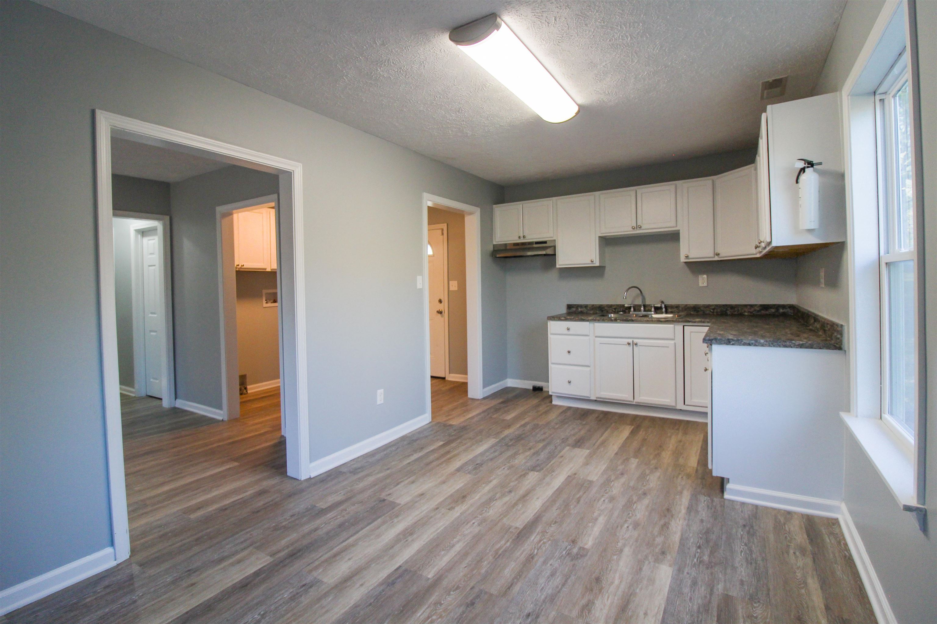 284 Highland Street Ripley, TN 38063 - Photo 6 of 23 Kitchen featuring white cabinets, a textured ceiling, dark wood-style floors, and under cabinet range hood