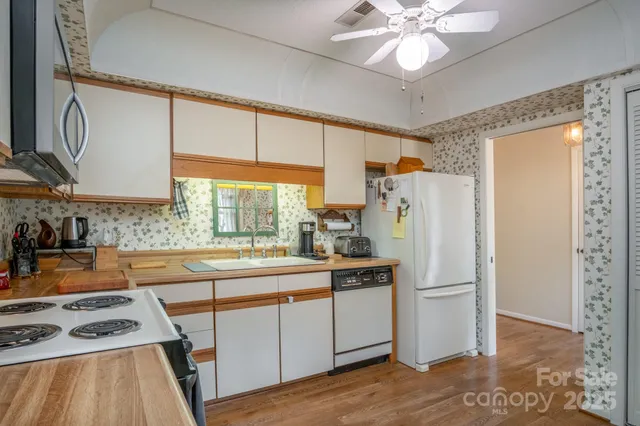 a kitchen with stainless steel appliances a refrigerator a sink a stove a dining table and chairs