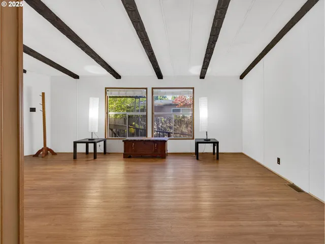 a view of an empty room with window and hardwood floor