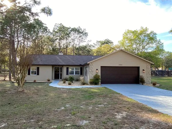 a front view of house with yard and trees in the background