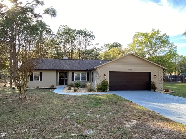 a front view of house with yard and trees in the background