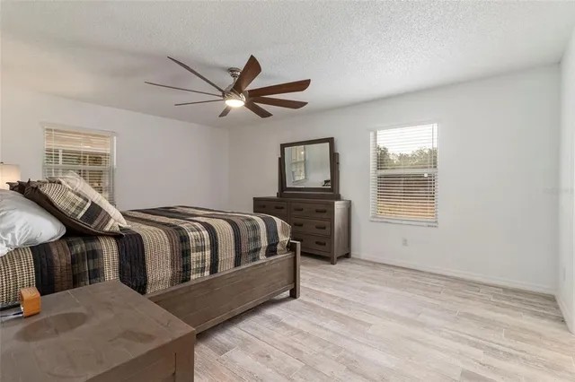 a spacious bedroom with a bed a dresser and a window