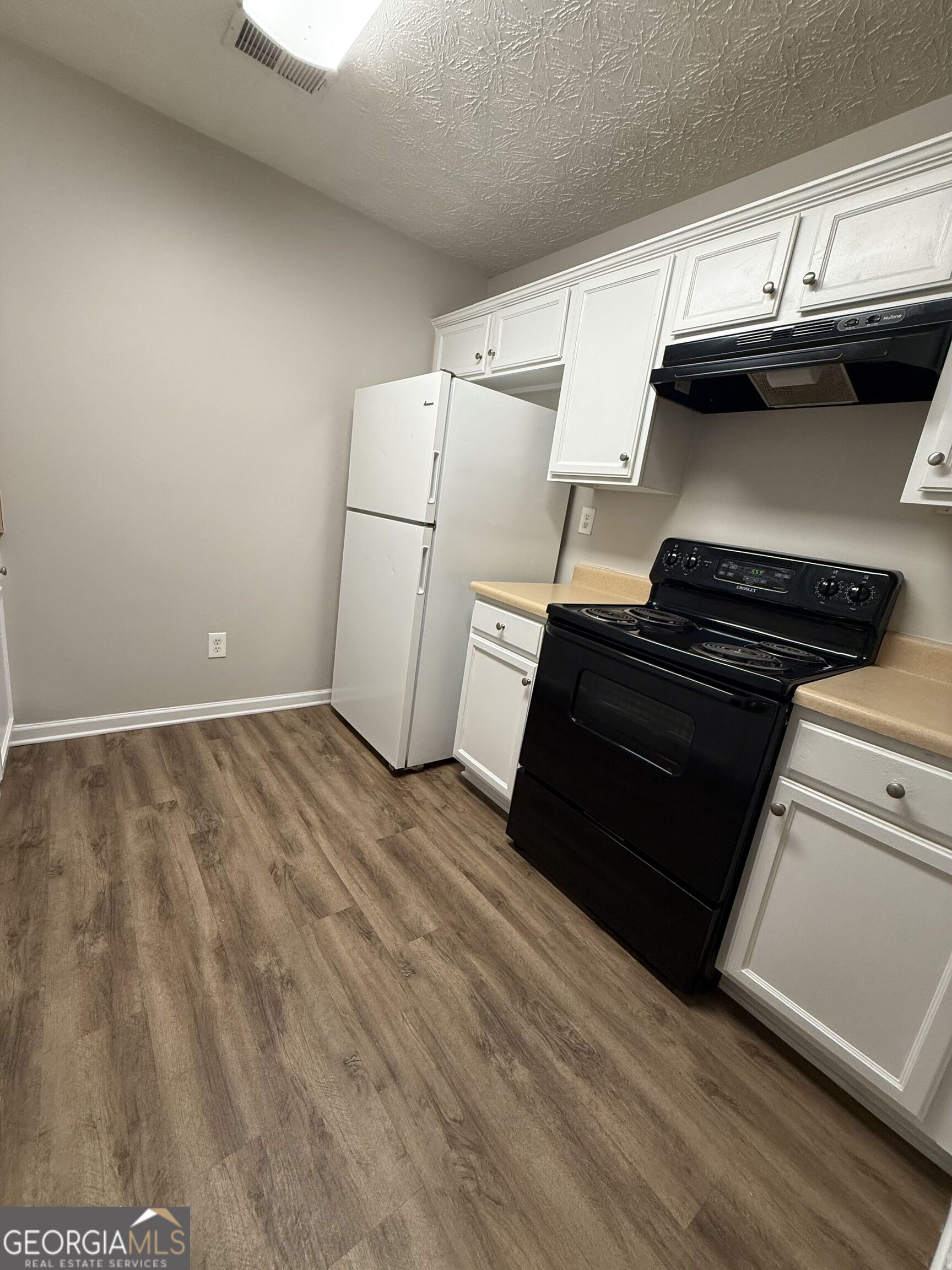 6132 Ruth Street Southwest Covington, GA 30014 - Photo 11 of 33 a view of a kitchen with wooden floor and electronic appliances