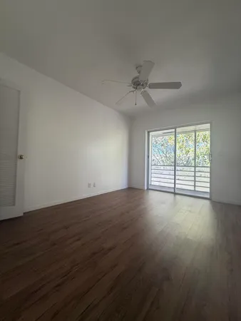 a view of an empty room with wooden floor and a window