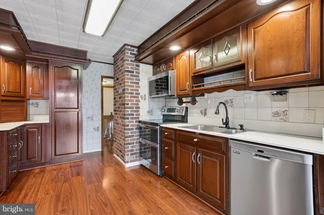 a kitchen with stainless steel appliances granite countertop a sink a stove a refrigerator cabinets and wooden floor