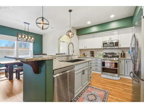 a kitchen with stainless steel appliances granite countertop a stove a sink and a wooden cabinets