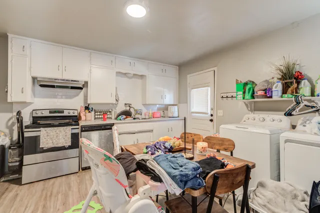 a kitchen with a table chairs stove and white cabinets