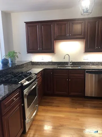 a kitchen with stainless steel appliances granite countertop a sink a stove a refrigerator and cabinets